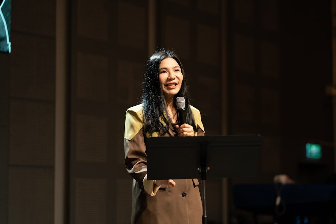 Moderator speaking on stage with microphone in front of an audience